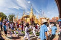 Buddhist people praying and walking around a golden pagoda.